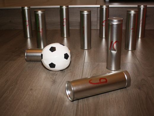 Genummerde blikken opgesteld als kegels, met een bal ervoor