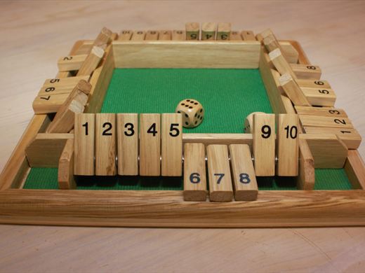 Het houten spel Shut the Box met genummerde klepjes en een dobbelsteen